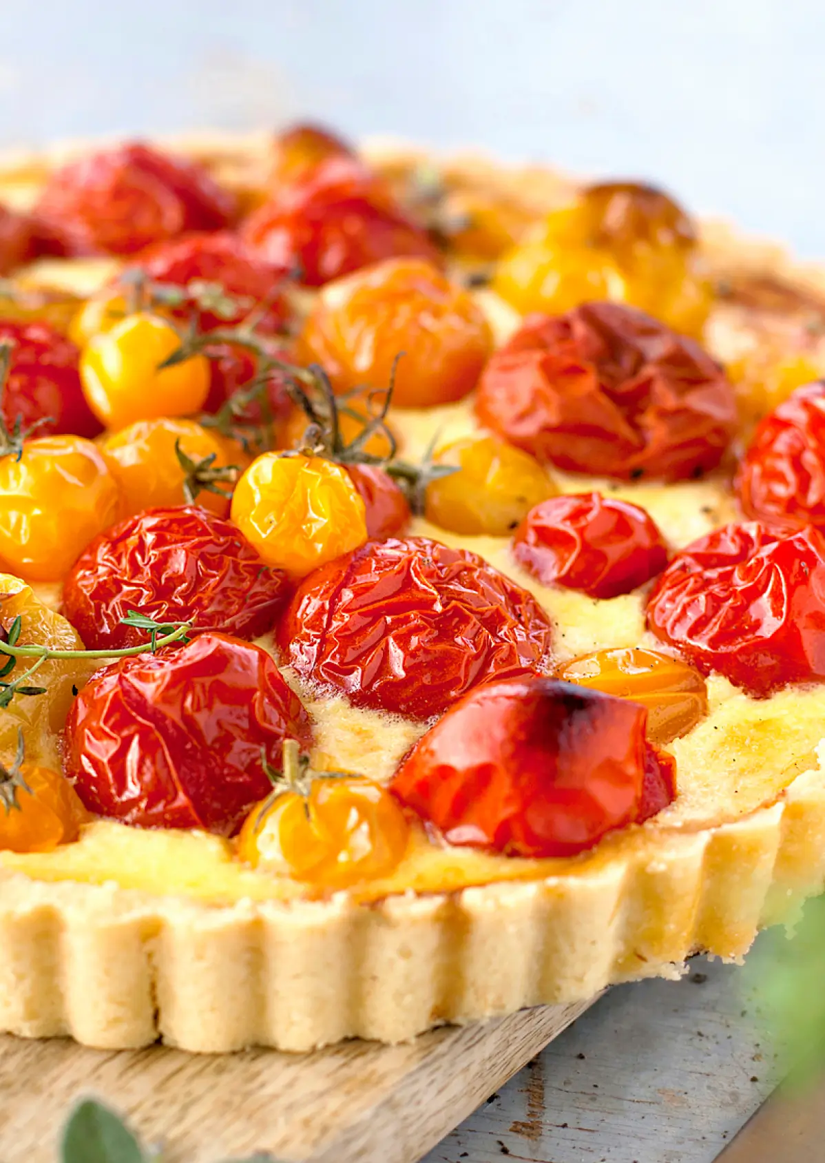 Roasted tomato and herb tart with caramelized red and yellow cherry tomatoes on a creamy custard filling in a fluted pastry crust.